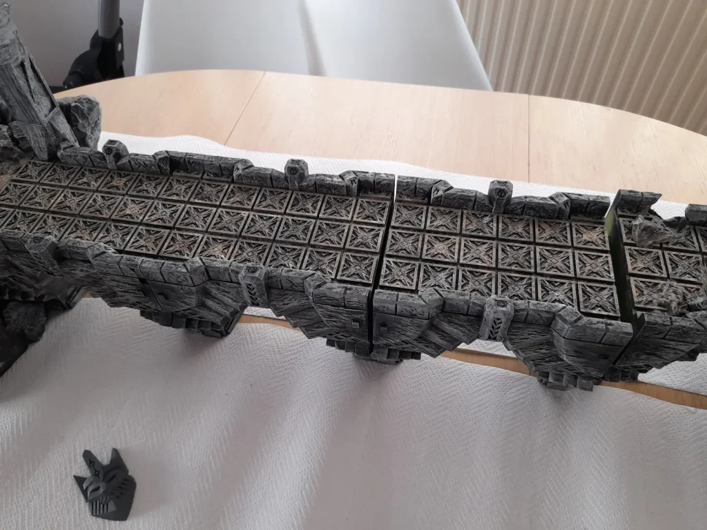 Mines of Maznar Modular Bridge – Assembly Test with Scatter Terrain Behind-the-scenes look at the 3D print testing setup for the Mines of Maznar modular bridge, showing bridge parts laid out on a table with assorted scatter terrain pieces to test fit and assembly process